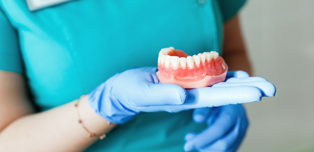 Hygienist holding set of dentures